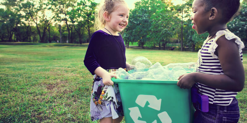 sustentabilidade nas escolas: duas crianças segurando um cesto de lixo reciclável