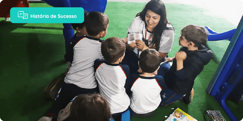 história de sucesso: professora agachada, brincando com os alunos no pátio da escola