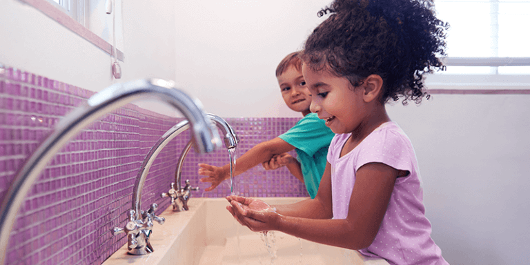 Crianças se prevenindo contra o coronavírus lavando as mãos no banheiro da escola