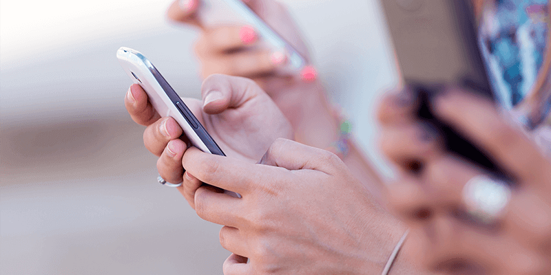 Mãos de alunos utilizando celular com agenda escolar digital