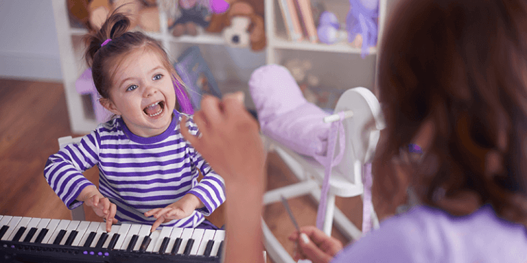 Menina criança tocando piano com ajuda de professora