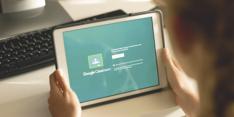 Imagem de uma pessoa segurando um tablet que mostra a tela inicial do Google Classroom